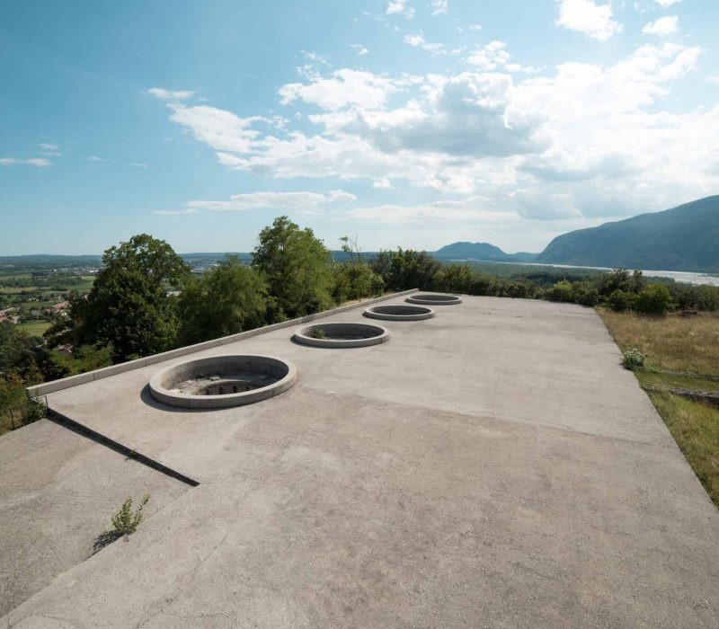Flat roof with circular skylights overlooking scenic landscape and mountains.